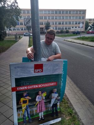 Unser Fraktionsvorsitzende Tony Sieg hängt gerade ein Plakat in Oranienburg auf.